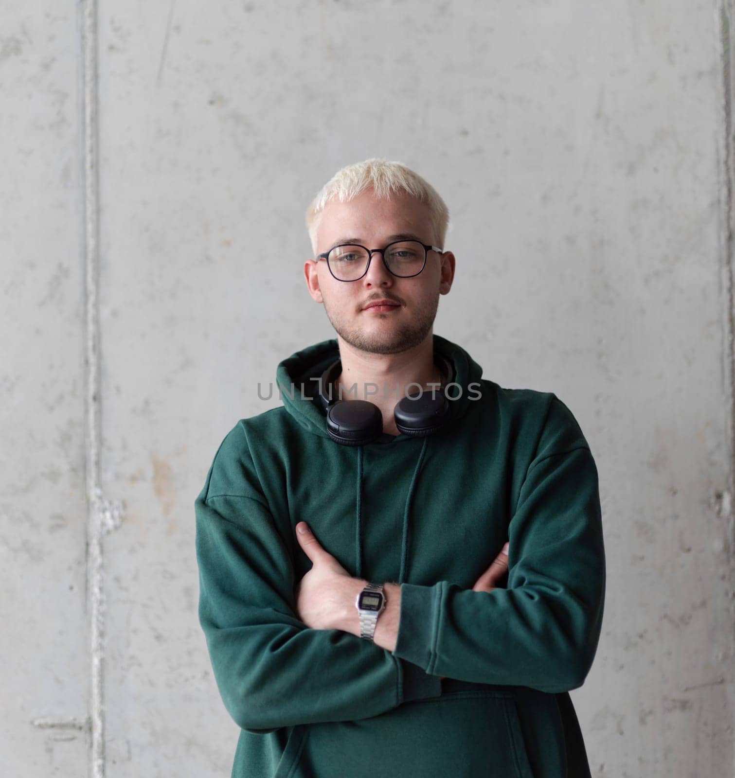 A man with blue hair, eyeglasses, and a green sweatshirt confidently poses with his arms crossed against a gray background, showcasing his fashionable and unique style. by dotshock