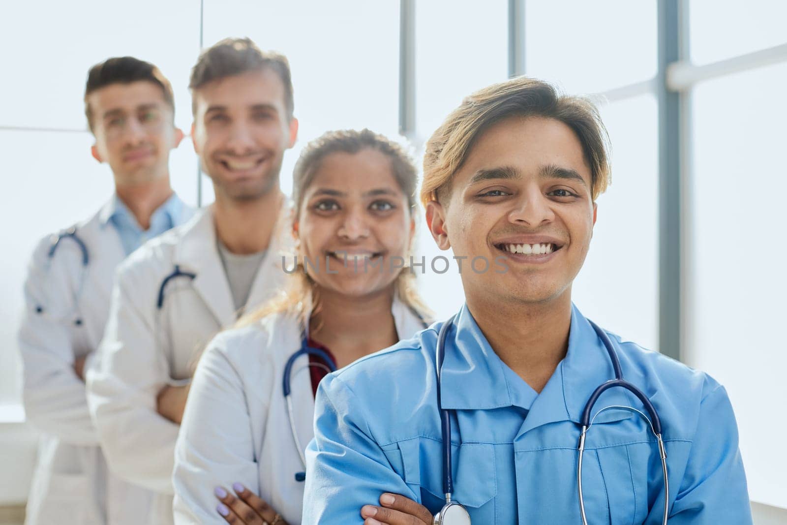 Successful team of medical doctors are looking at camera and smiling while standing in hospital