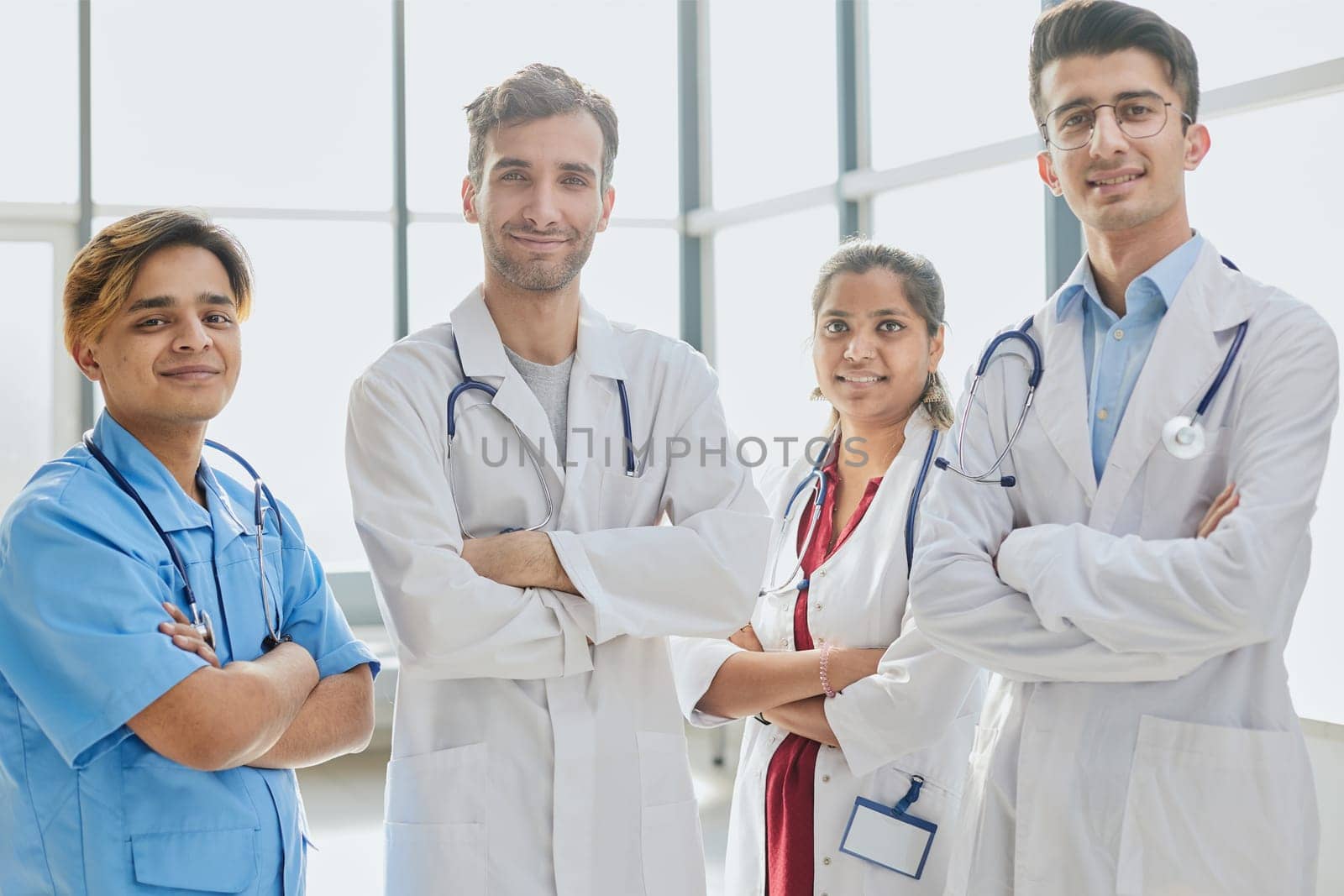 Successful team of medical doctors are looking at camera and smiling while standing