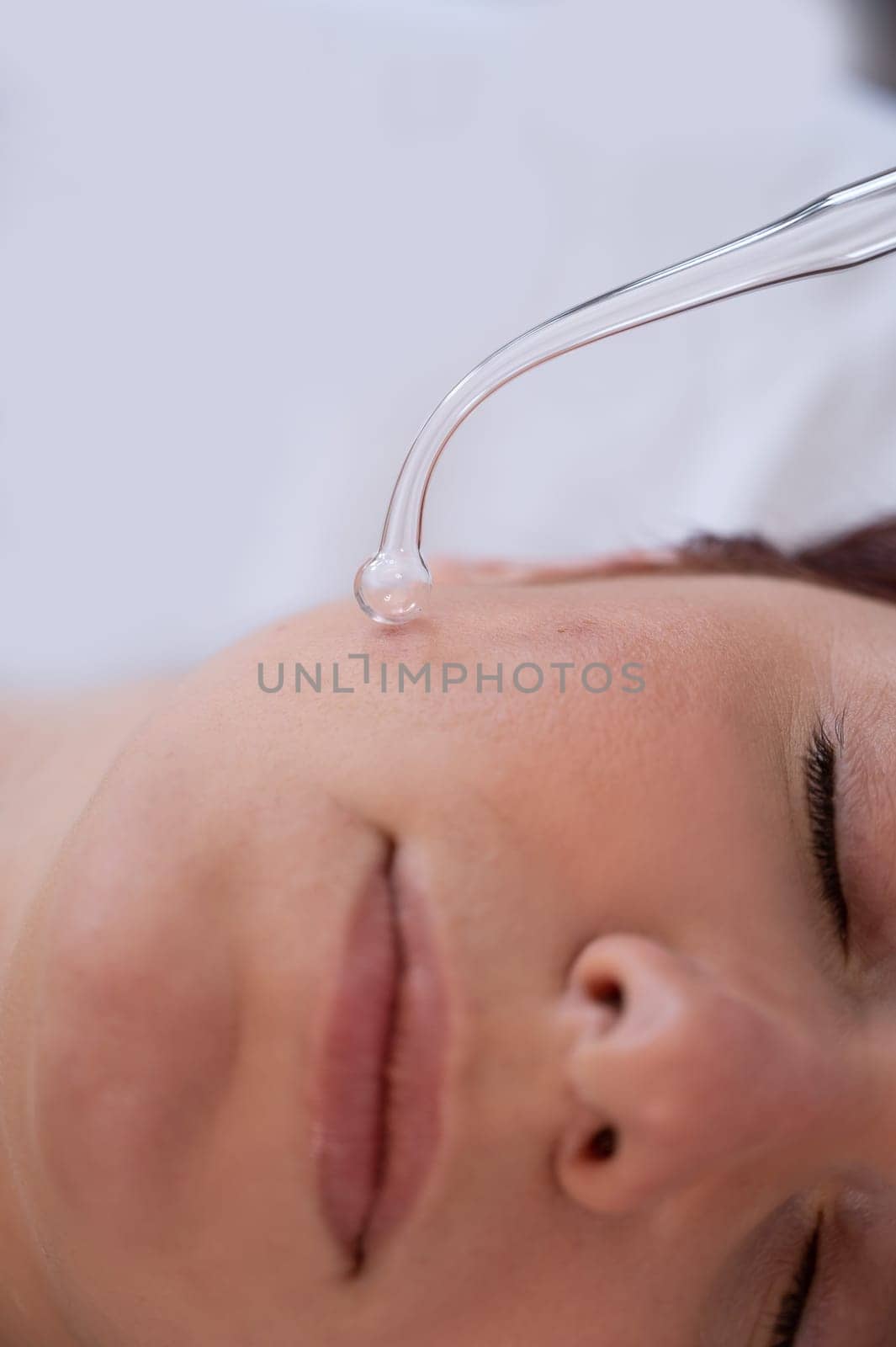 The doctor uses the darsonval apparatus against acne on the face of a female patient