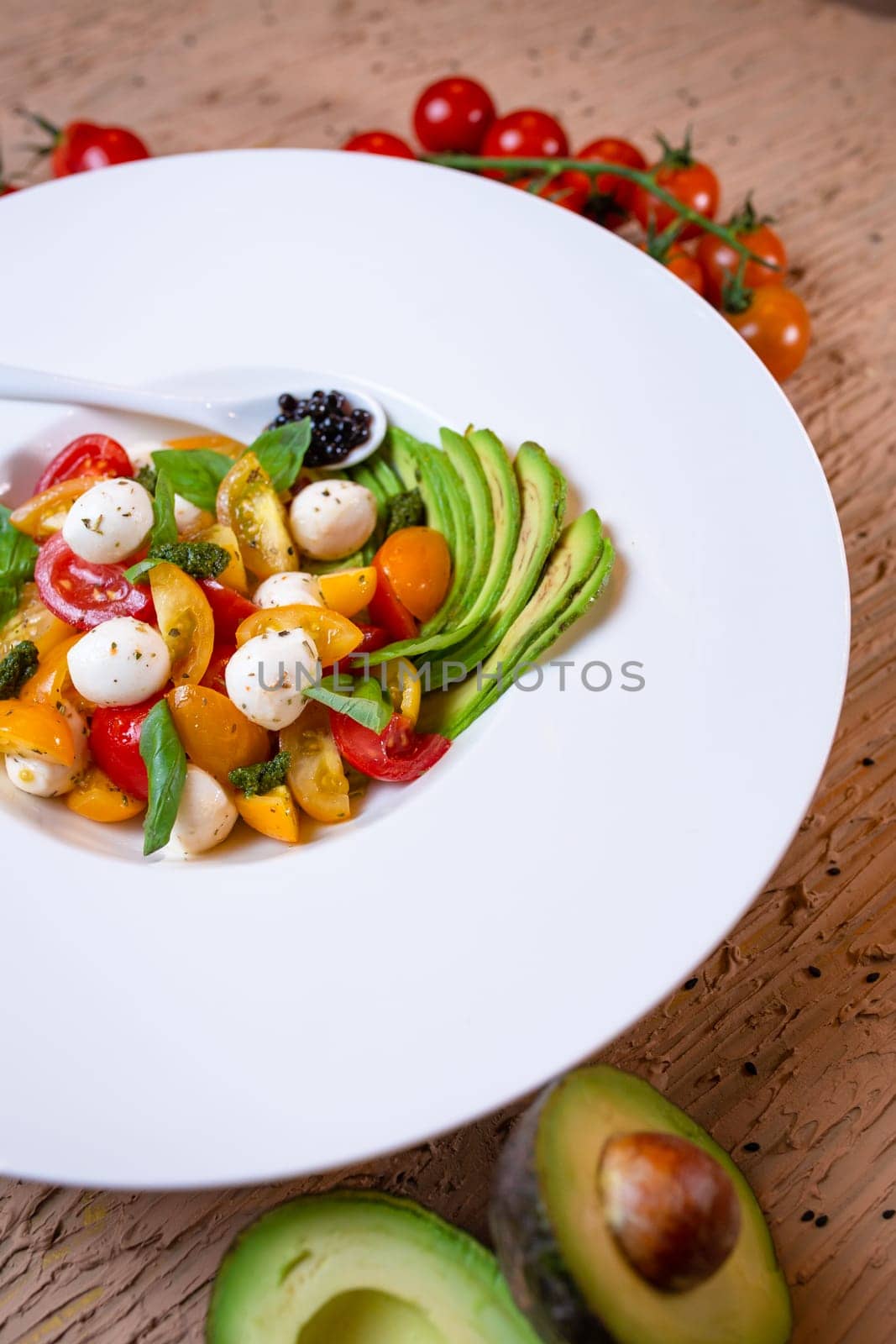 top view salad with avacado, mozzarella and tomatoes in a white plate by Pukhovskiy