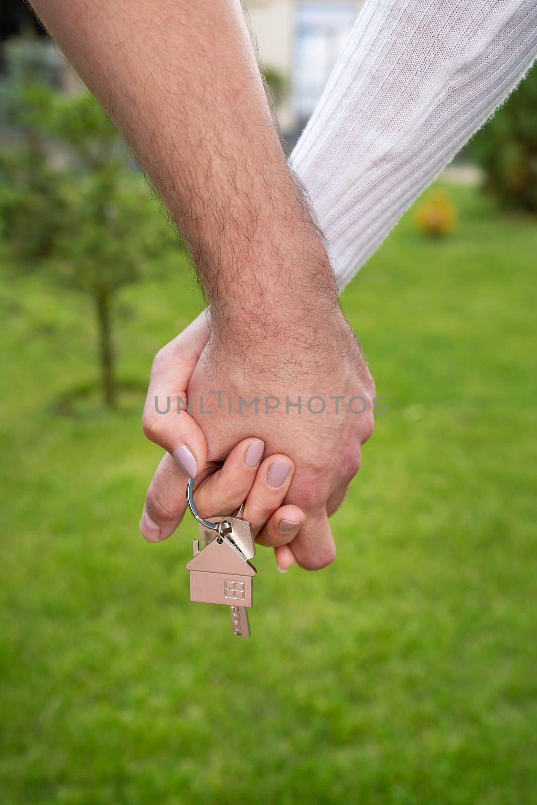 A happy young couple rejoices in buying an apartment, the couple holds in their hands the keys to their new house, a metal keychain in the form of a house. Buying a house, apartment