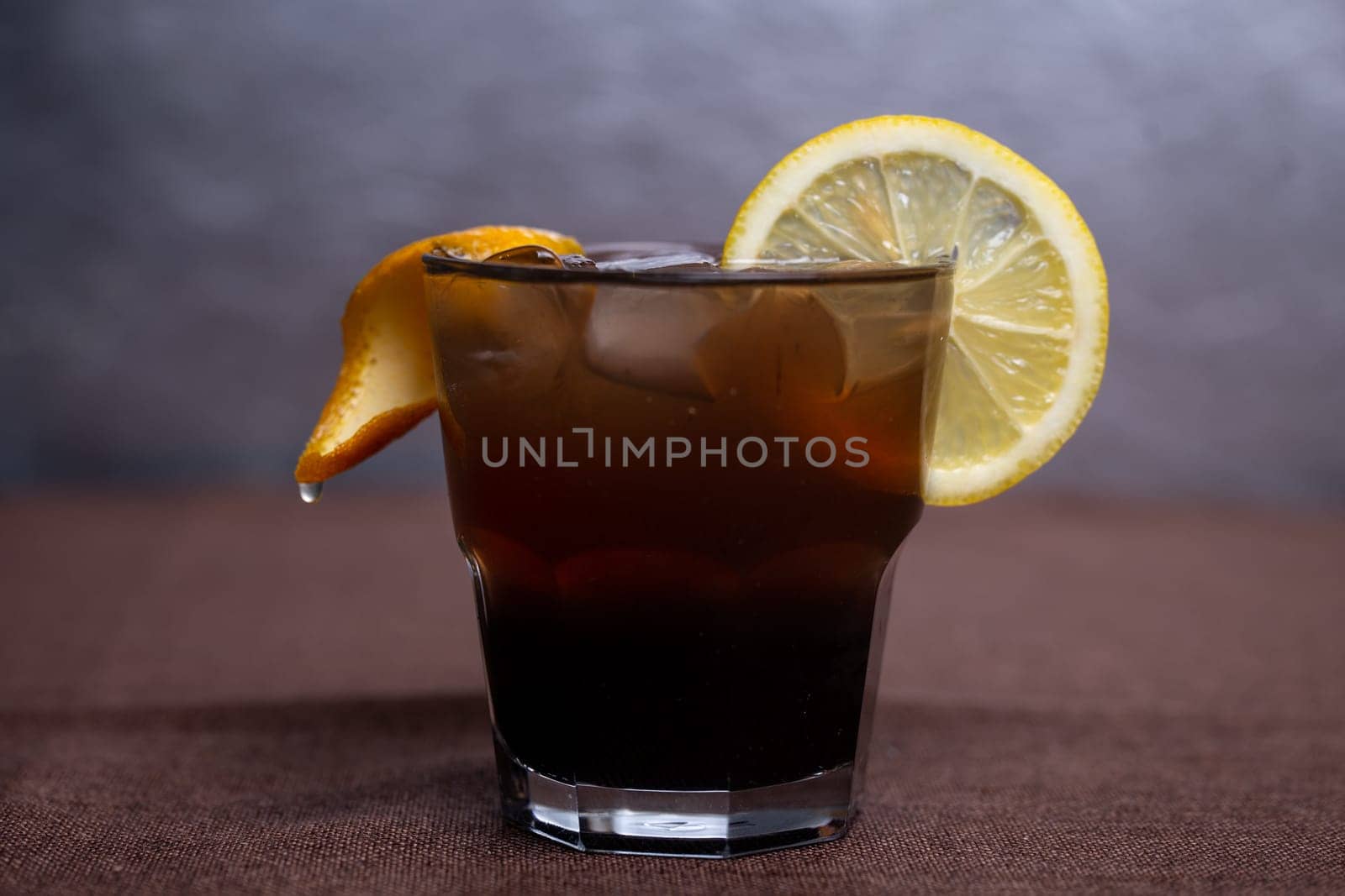 alcoholic drink with Cola and a slice of lemon in a glass.