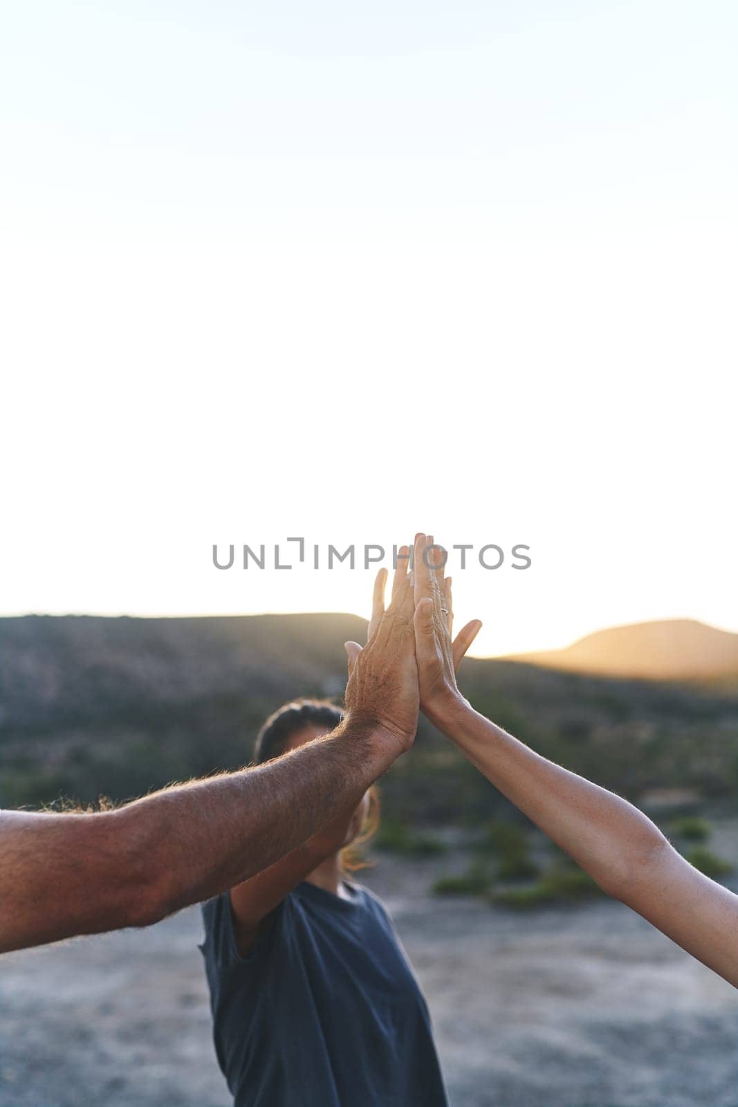 Get hands on in growing your family bond. a family joining their hands in solidarity outdoors. by YuriArcurs