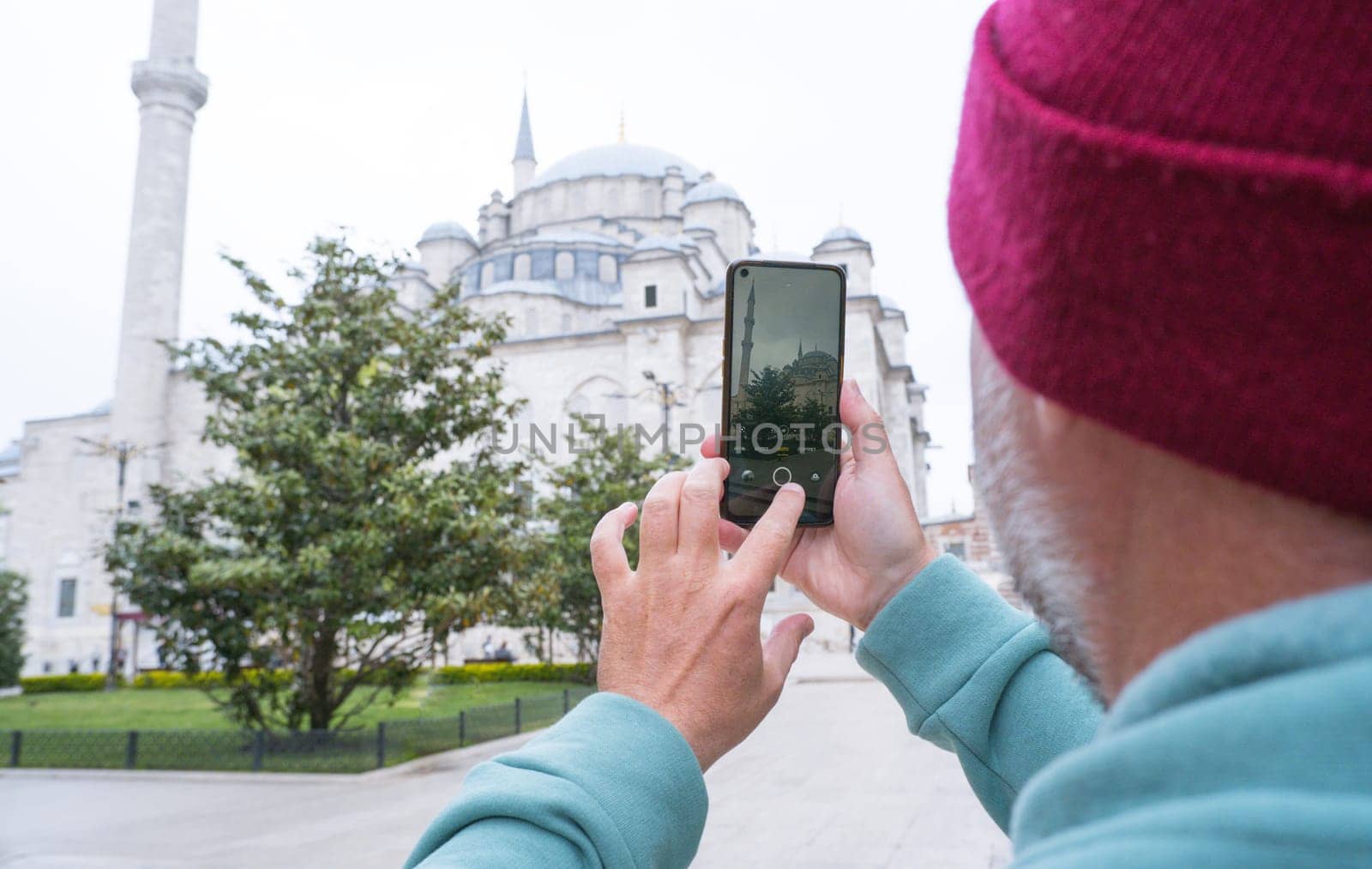 A male tourist takes a photo of the Fatih Mosque in Istanbul, Turkey as a keepsake