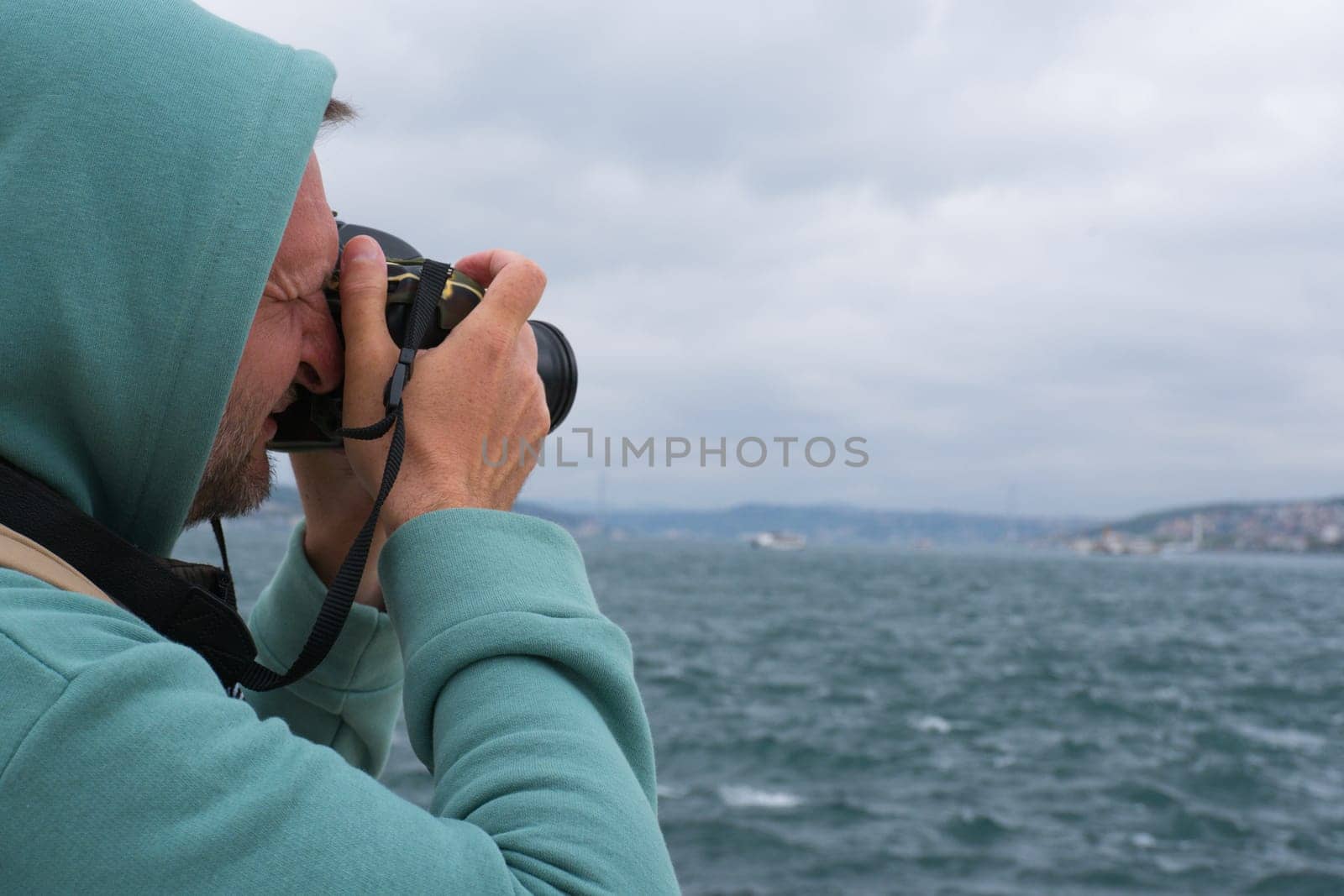 A male tourist photographs the landscape on the Bosphorus embankment in Istanbul, Turkey, as a keepsake