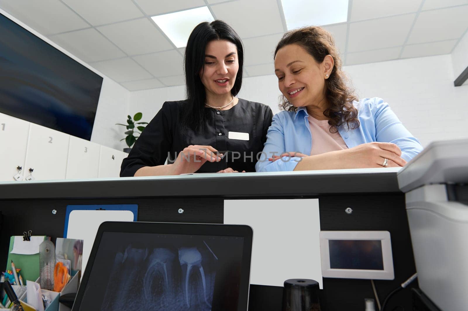 Confident experienced dentist prescribing to her patient the dental treatment that needs to perform in dentistry clinic by artgf