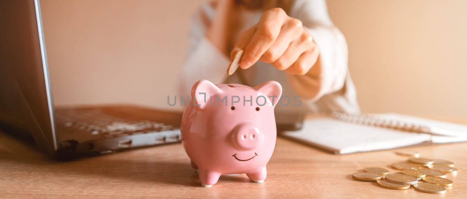 A young girl makes calculations, checks her finances, makes notes in a notebook and sets aside some of the funds, savings in a piggy bank for personal expenses and future development.