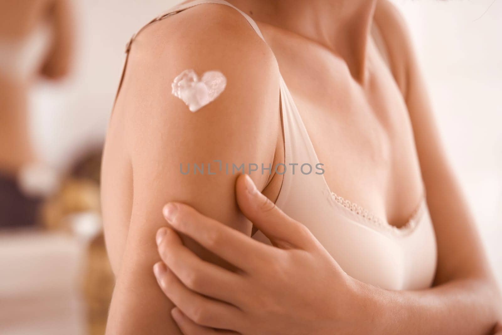 A young girl applies a moisturizer to her skin, a woman gently cares for her body, depicts a heart with a cream, taking care of herself, beauty and health.