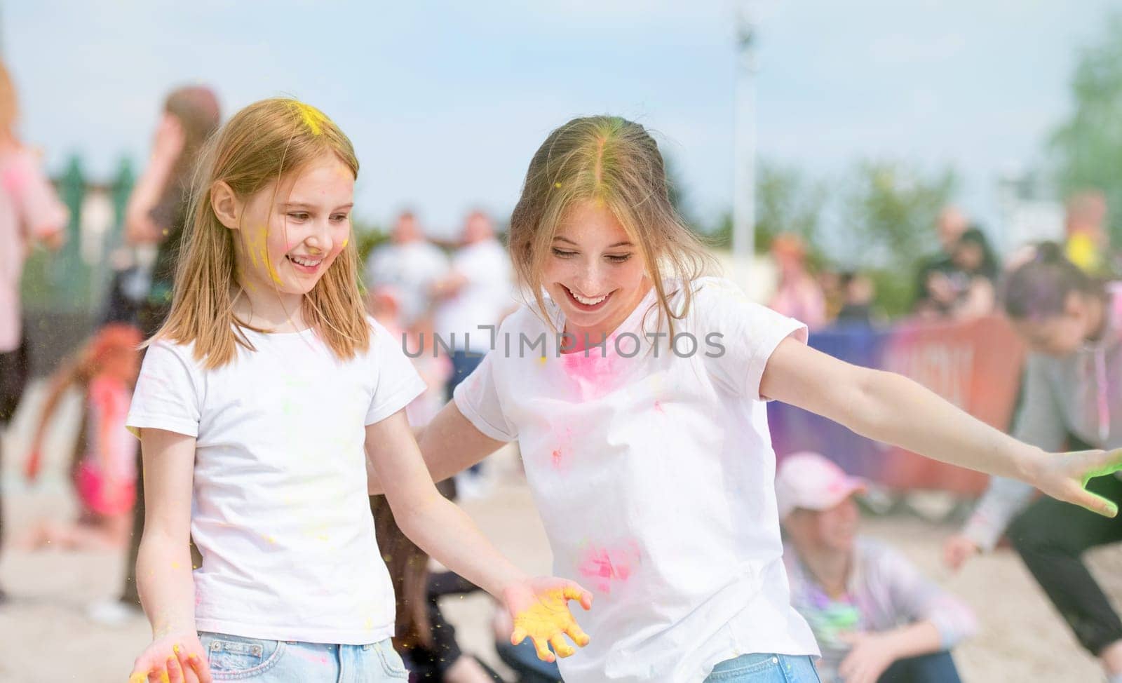 Pretty girls sisters in indian traditional Holi festival with colorful powder smiling. Female teenager and preteen child friends enjoying holiday