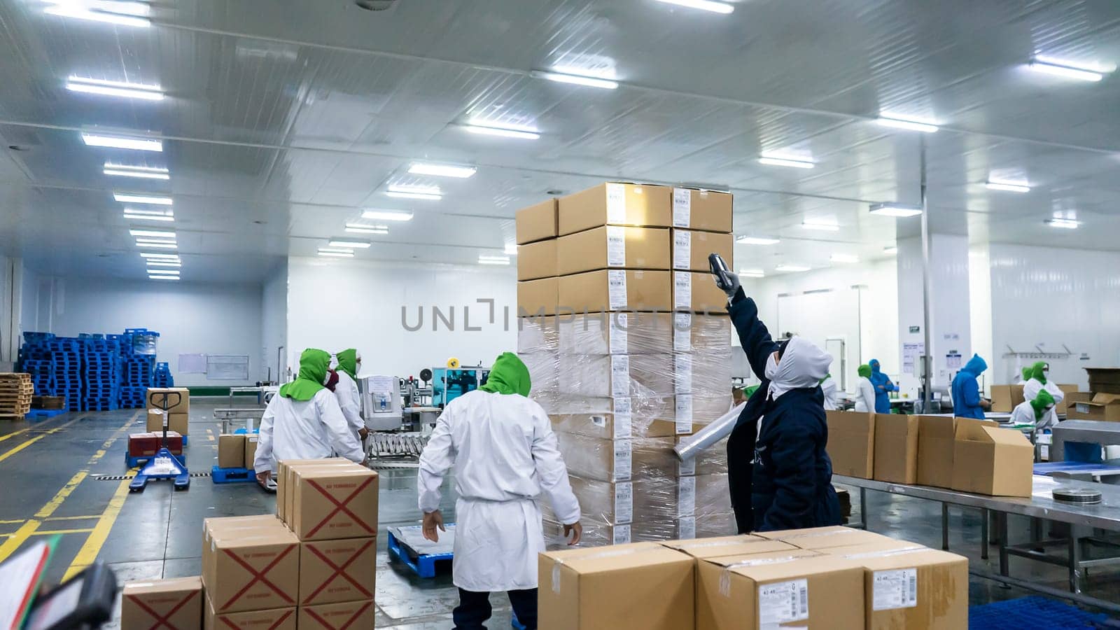 Unrecognizable Latino workers packing and securing cardboard boxes at a food production plant