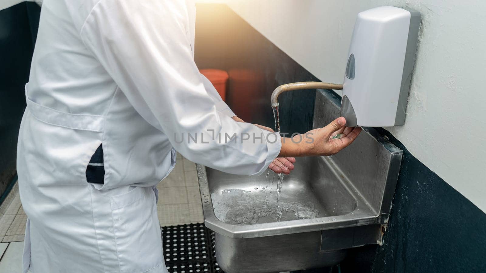 Engineer working in a food plant sanitizing his hands before starting the production process