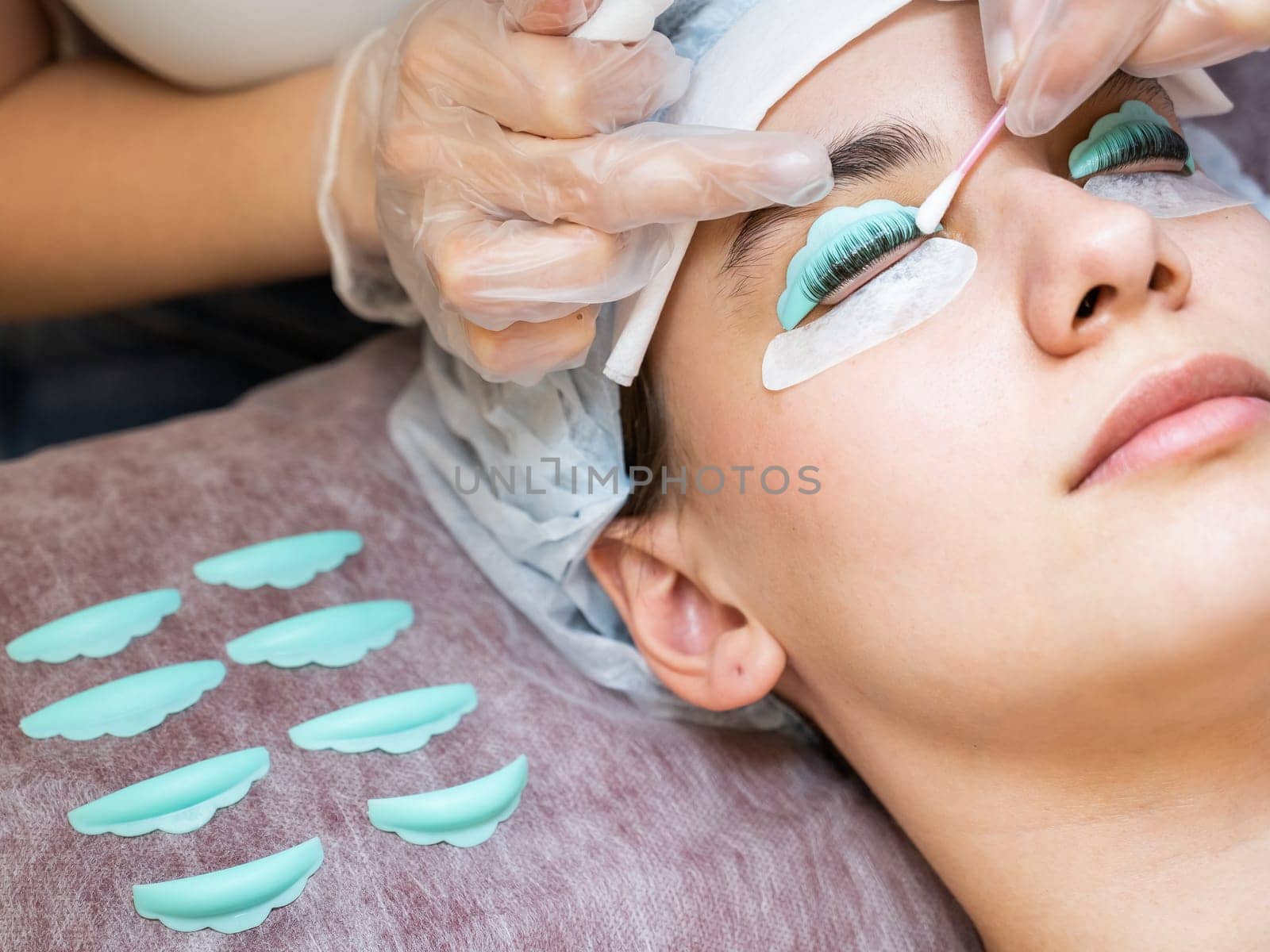 The master removes the composition for lamination from the client's eyelashes with a cotton swab. Eyelash perm procedure