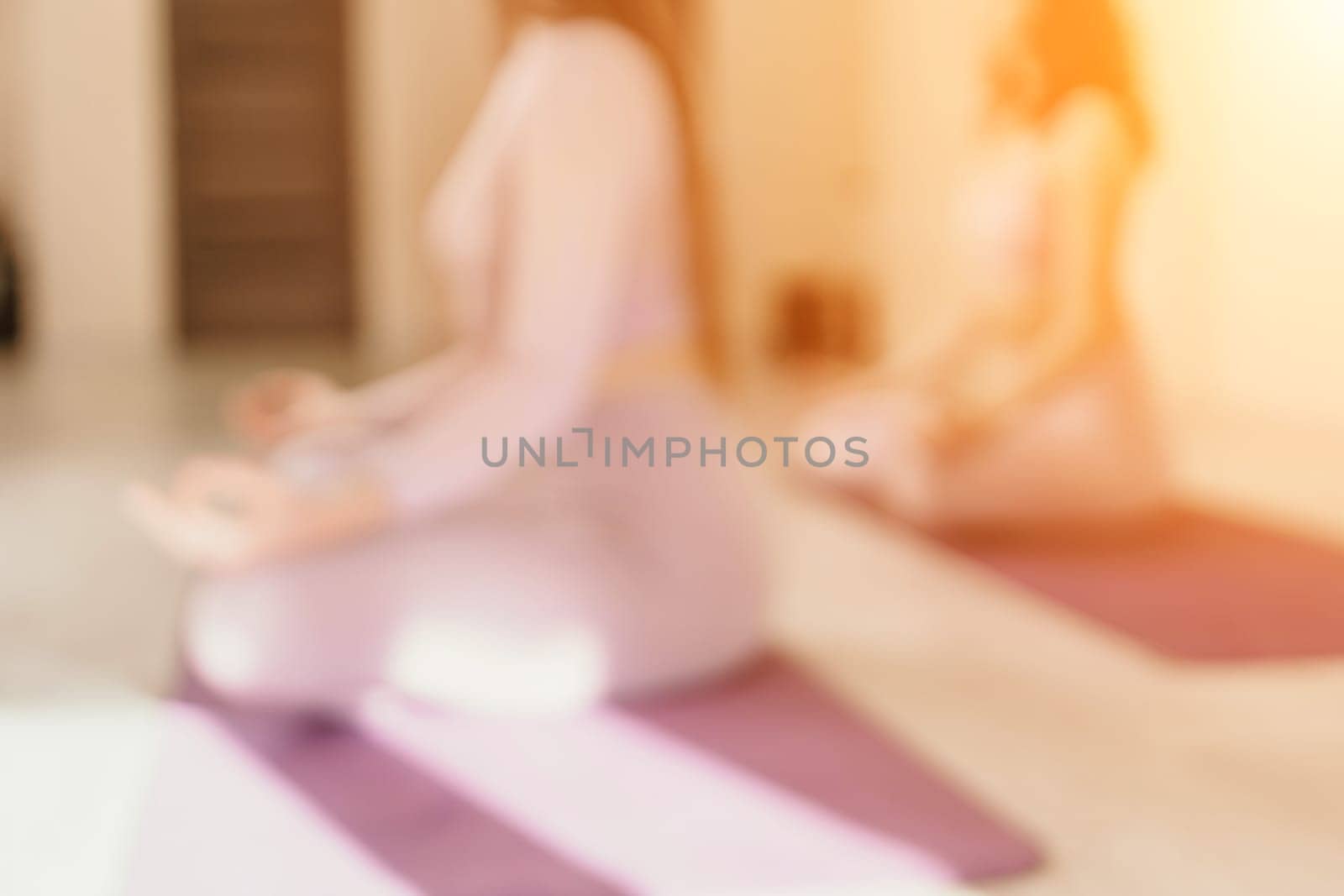 Abstract defocused foto of two young sporty woman, fitness instructor in pink sportswear doing stretching and pilates on yoga mat in the studio with mirror. Female fitness yoga routine concept. by panophotograph