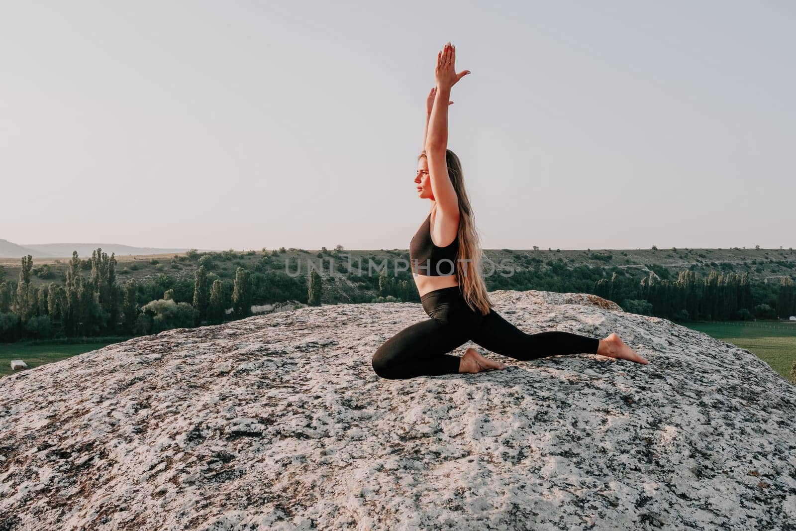 Fitness woman. Well looking middle aged woman with long hair, fitness instructor in leggings and tops doing stretching and pilates on the rock near forest. Female fitness yoga routine concept. by panophotograph