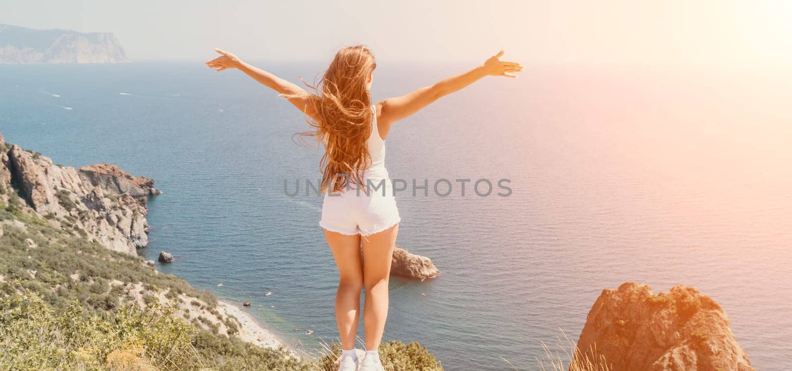 Woman travel sea. Young Happy woman in a long red dress posing on a beach near the sea on background of volcanic rocks, like in Iceland, sharing travel adventure journey