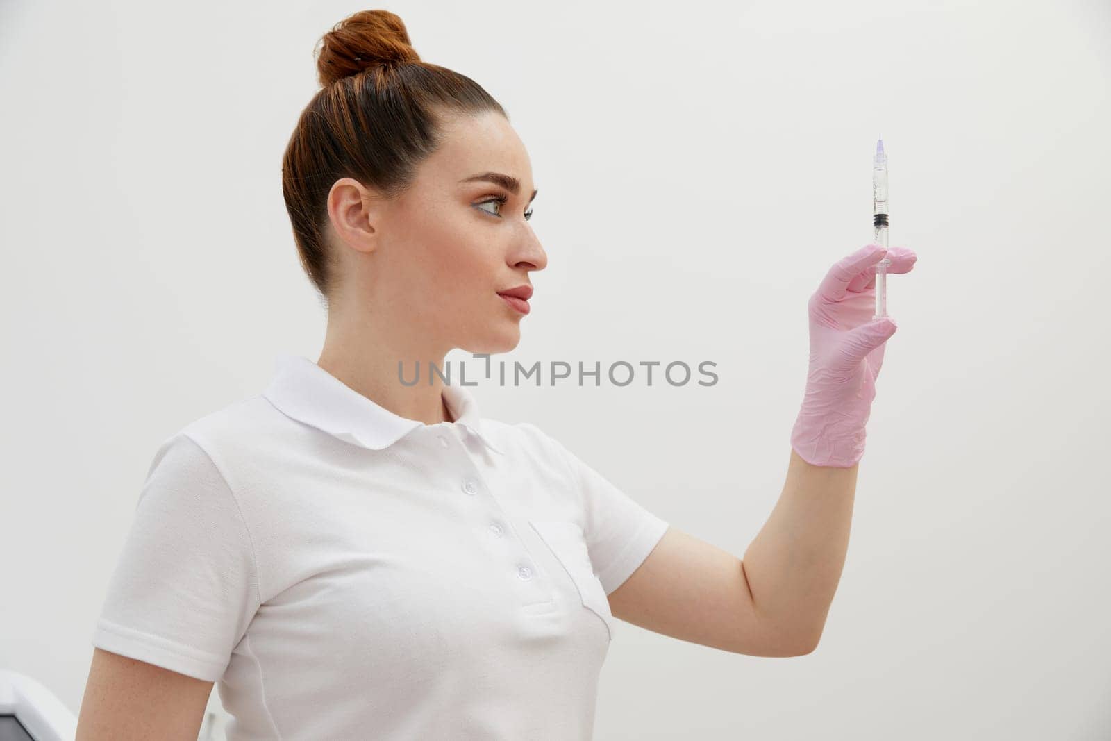 Cosmetologist holds syringe for injection with collagen hyaluronic filler for face or lips rejuvenation by Mariakray
