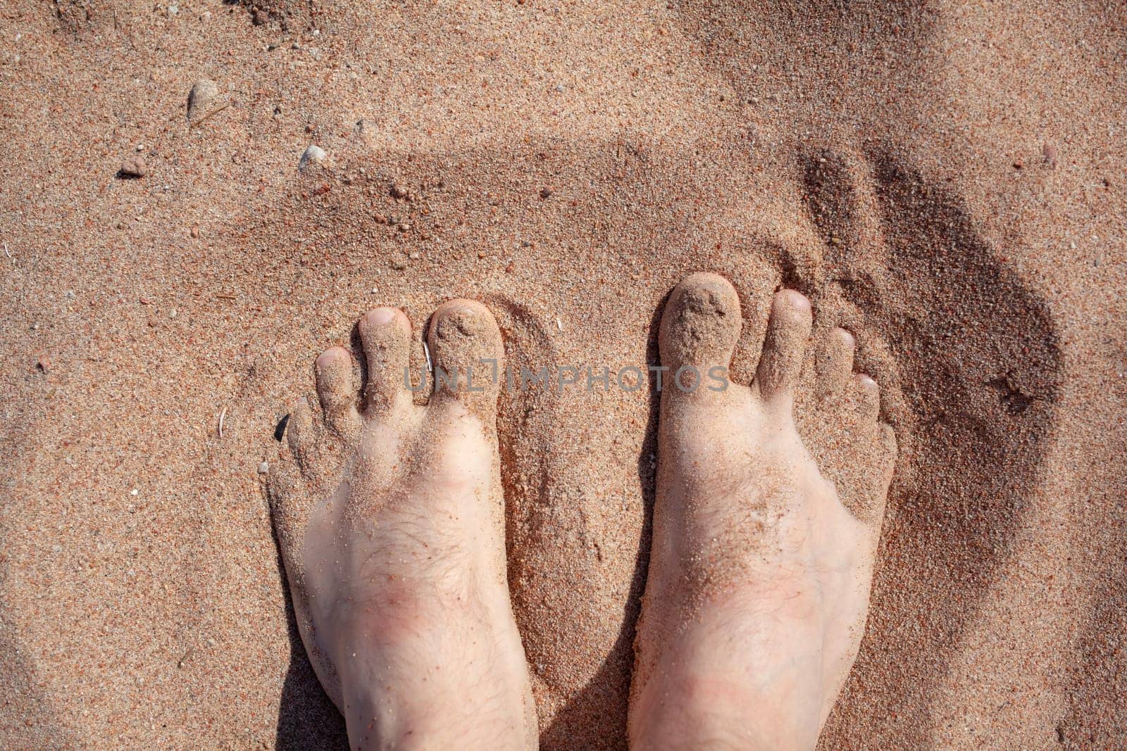 Top view of feet in the sand on a sledge. A woman or a man is standing by AnatoliiFoto