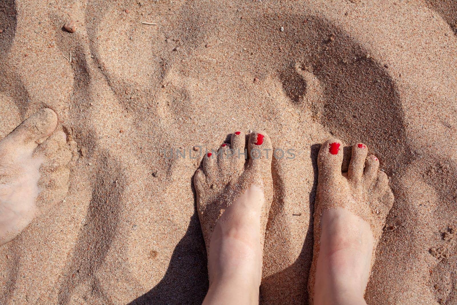 Top view of feet in the sand on a sledge. A woman or a man is standing on the sand. Summer holidays.