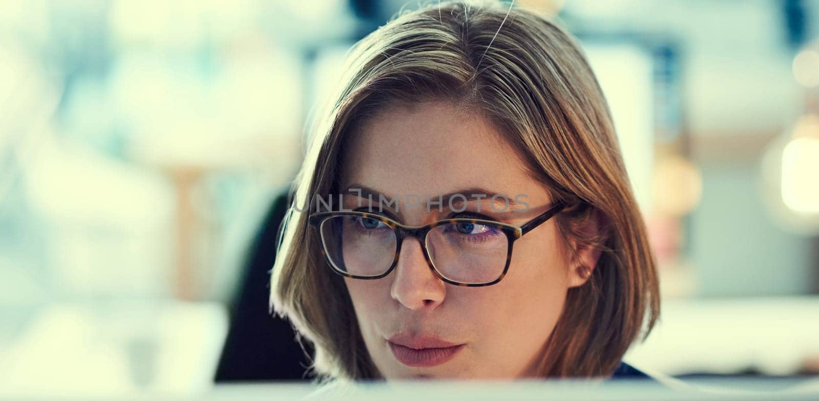 Focused on creating success. a young businesswoman working late in an office. by YuriArcurs