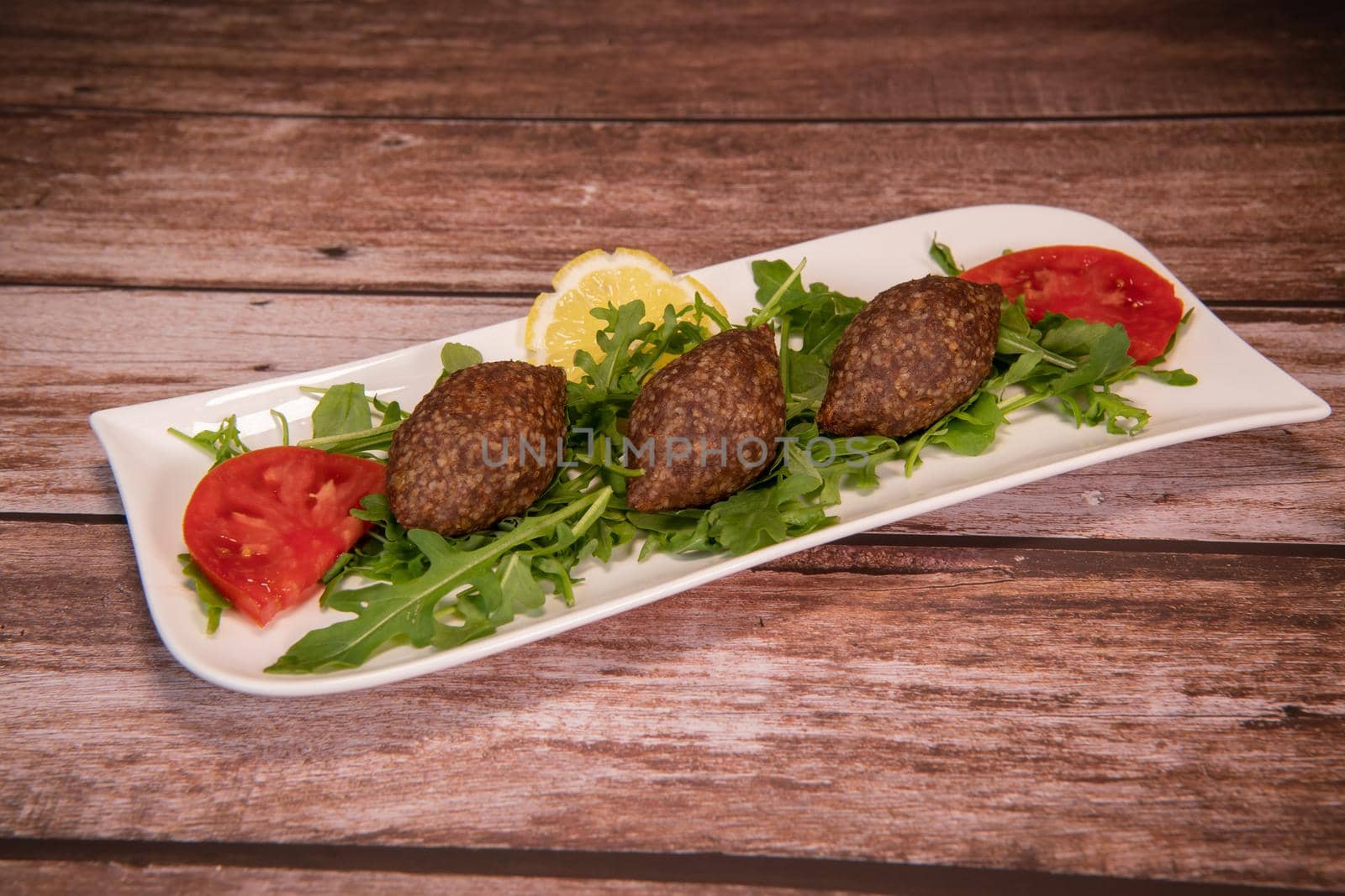 Traditional kebbe and pita bread on big round plate in lebanese restaurant. High quality photo