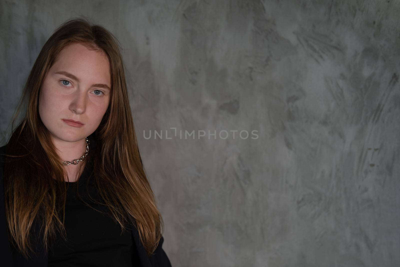 portrait of beautiful confident brunette woman in black in grey dark room. business woman. feminine. millennial people. stylish fashion clothes.