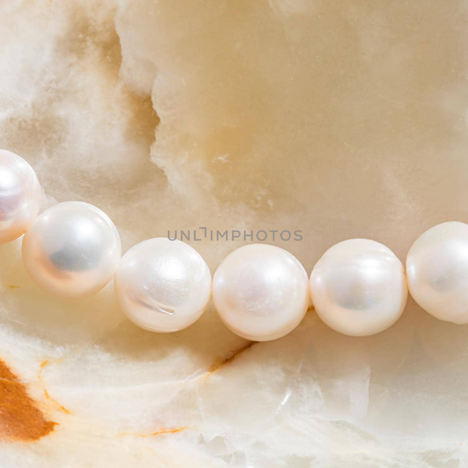 Nature white string of pearls on marble background in soft focus, with highlights by Olayola