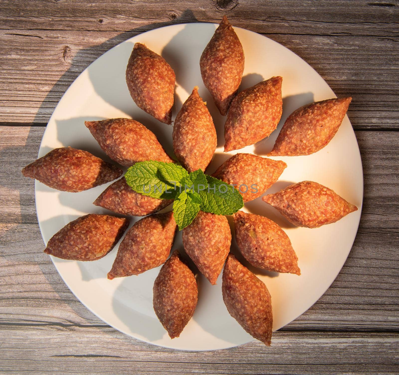 Traditional kebbe and pita bread on big round plate in lebanese restaurant. High quality photo