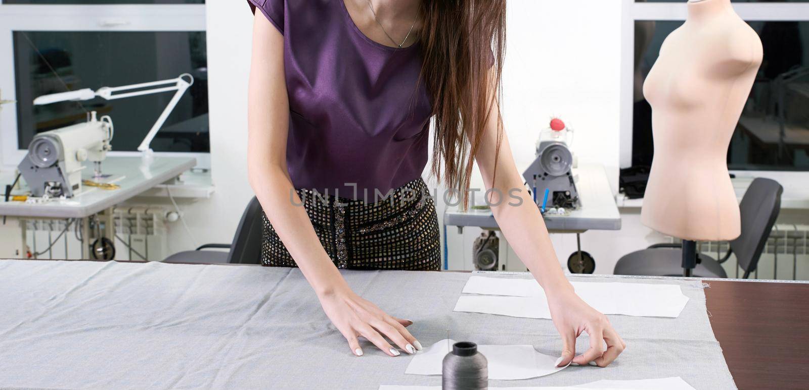 Cropped view of Tailor at work, drawing line on fabric with chalk in atelier studio by Mariakray