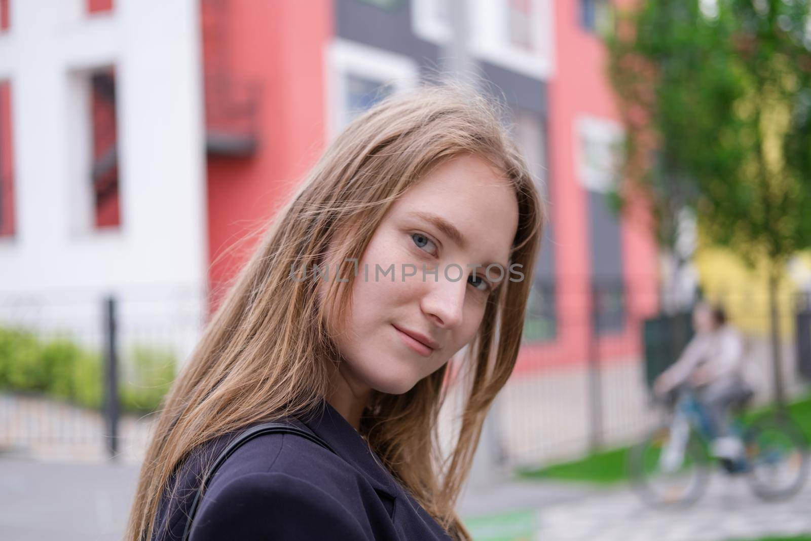 portrait of confident attractive brunette woman in black on background of colorful bright buildings. business woman. feminine. millennial people.