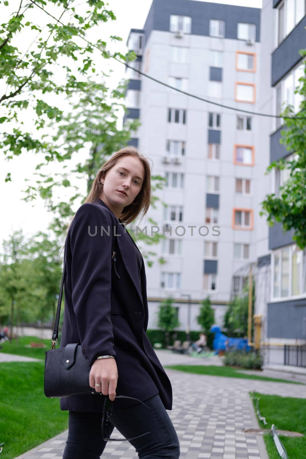 pretty brunette woman on background of bright modern buildings. feminine. millennial people. lady on walk.