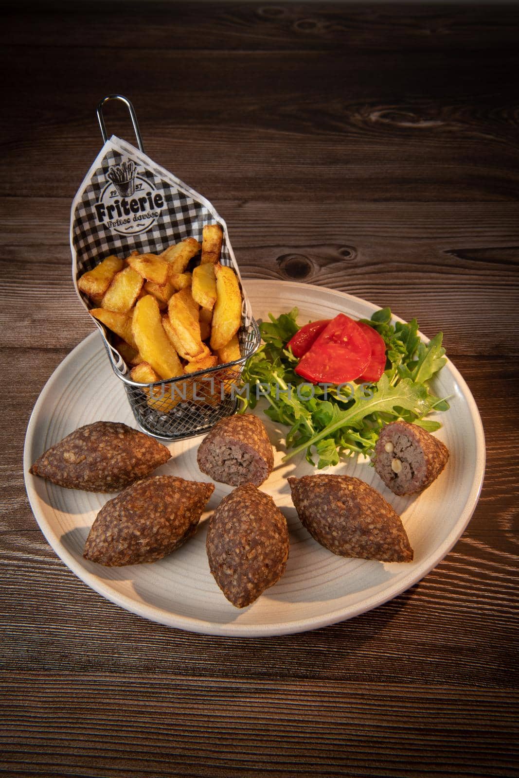 Traditional kebbe and pita bread on big round plate in lebanese restaurant. High quality photo