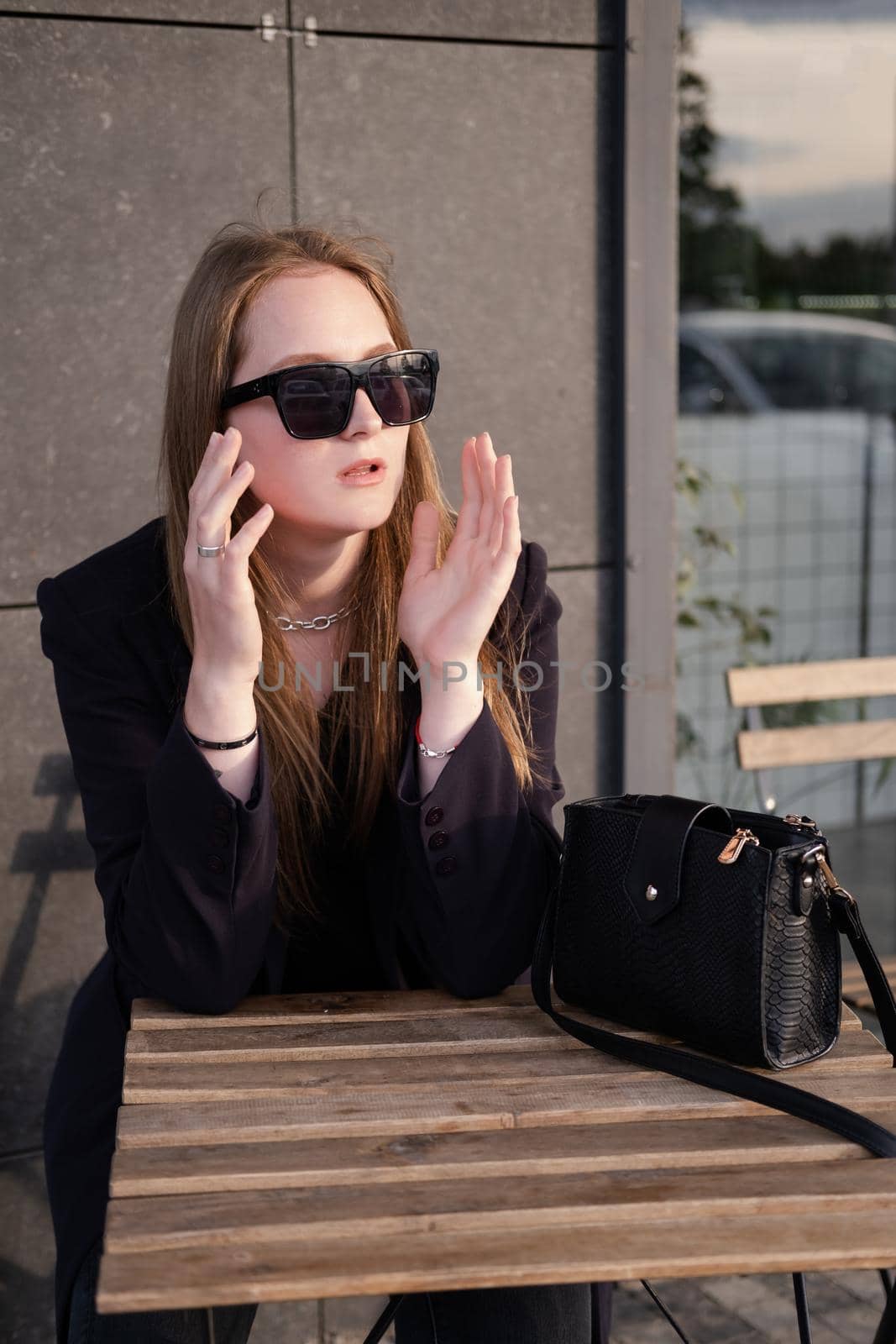 pretty brunette woman sitting by wooden table outside. feminine. millennial people. lady on coffee break.