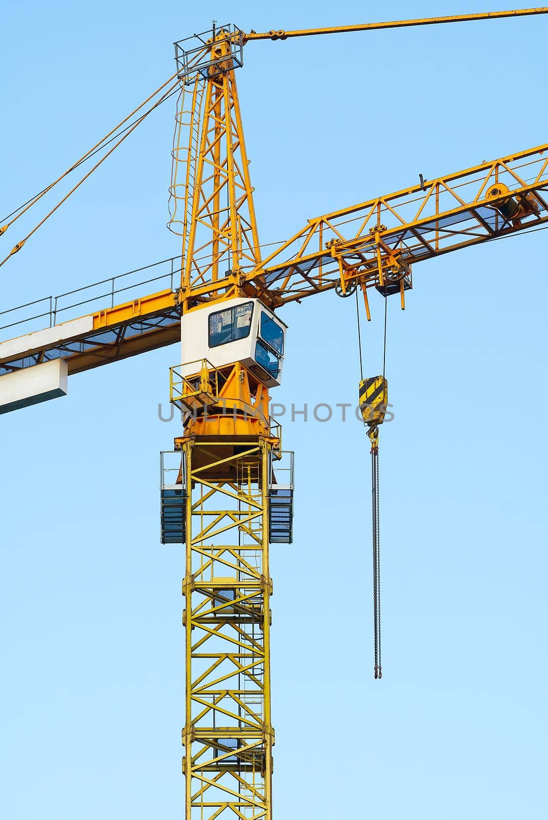 Construction tower crane on blue sky background. Yellow tower crane. Industrial construction crane. Tower cranes against blue sky.