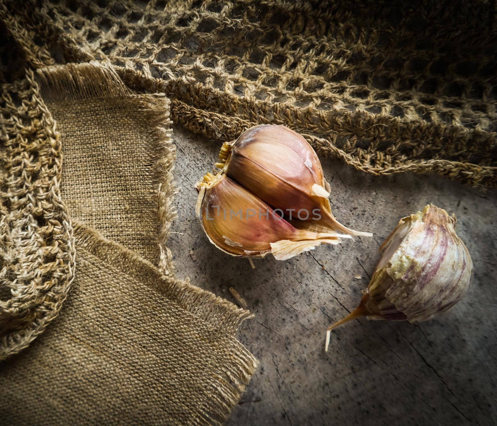 Garlic cloves and natural linen napkin on rustic wooden background