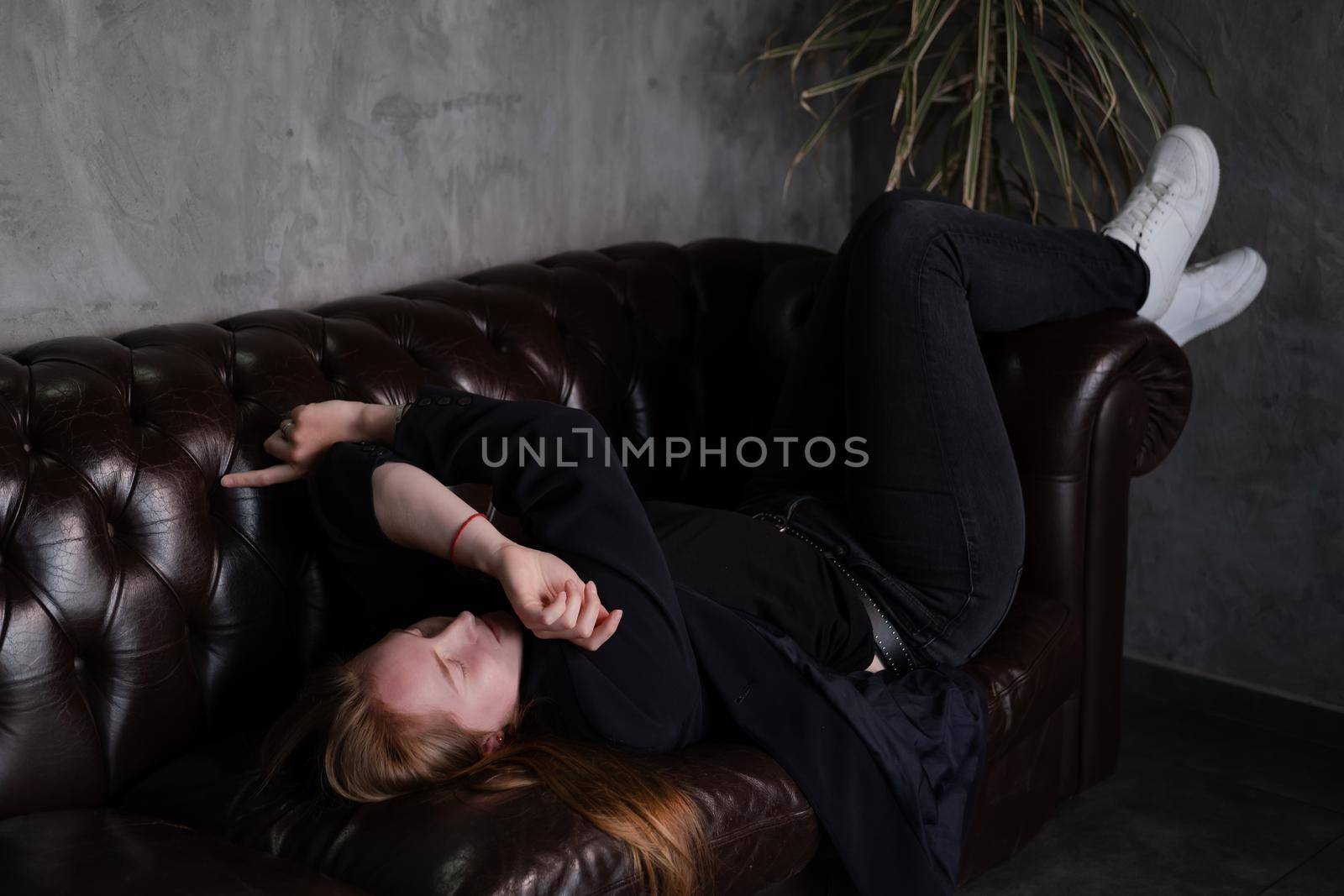 portrait of beautiful confident brunette woman in black in grey dark room. business woman. feminine. millennial people. stylish fashion clothes.