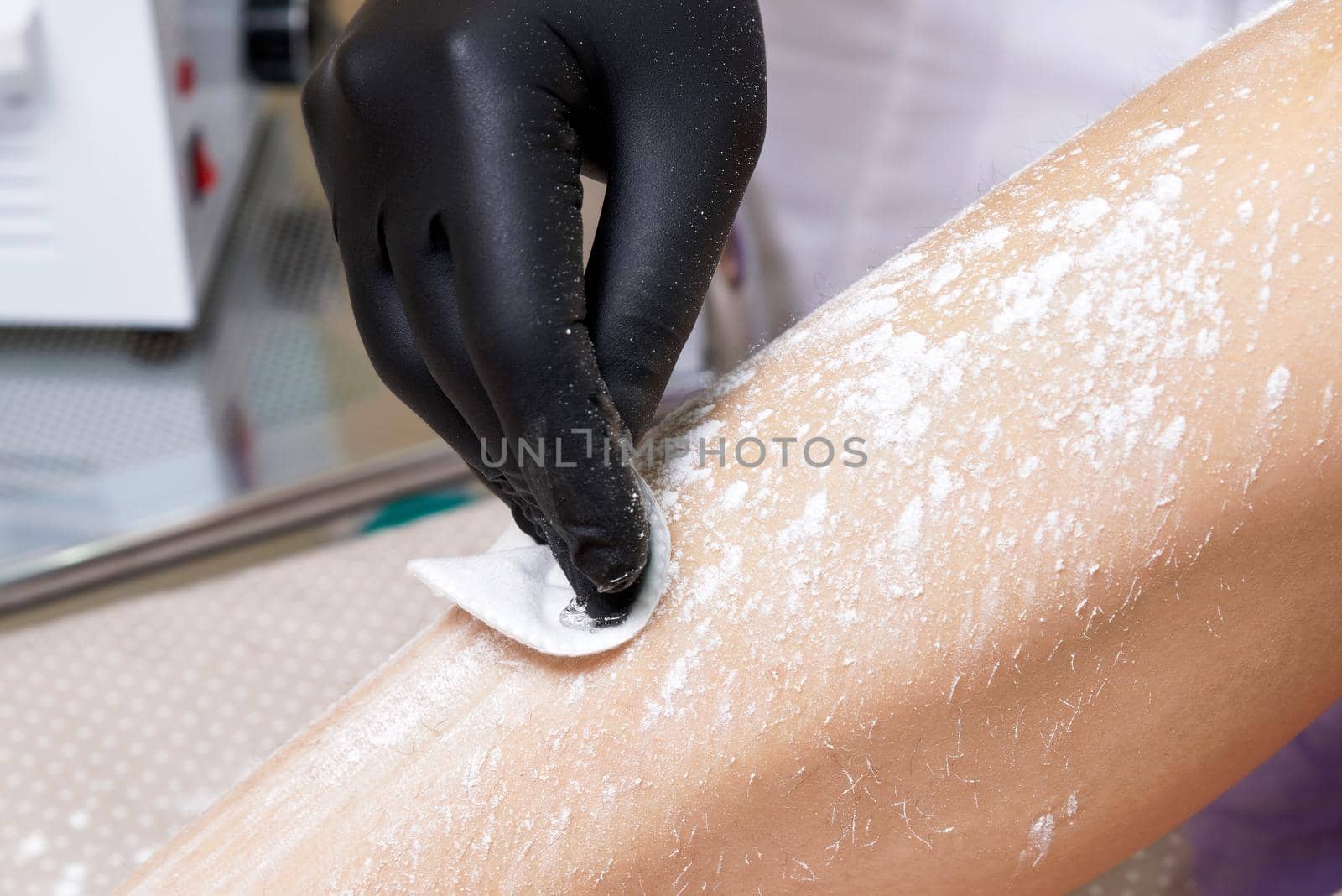 Beautician getting ready to wax female legs in spa center