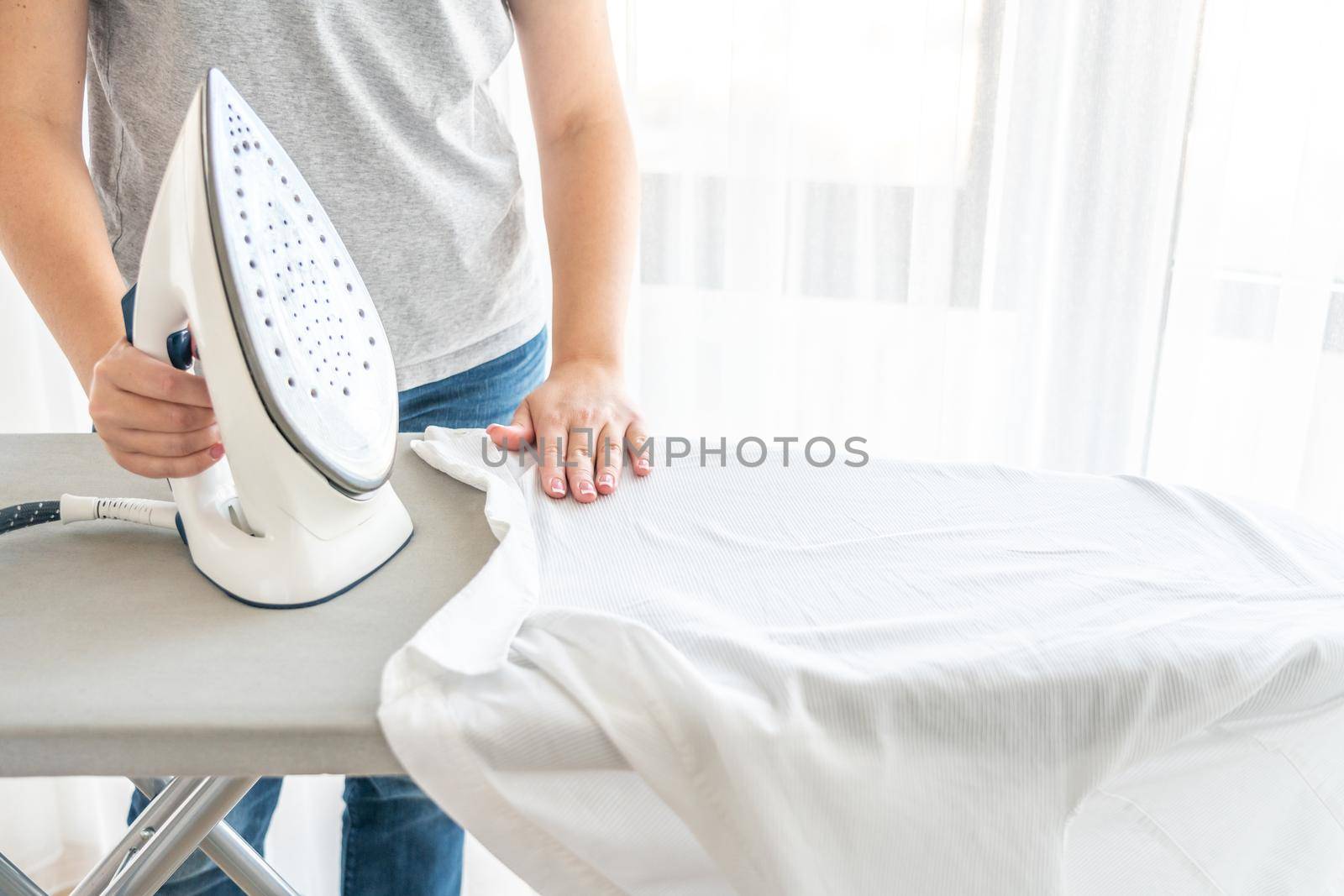 Close up of Female hands ironing white shirt on ironing board