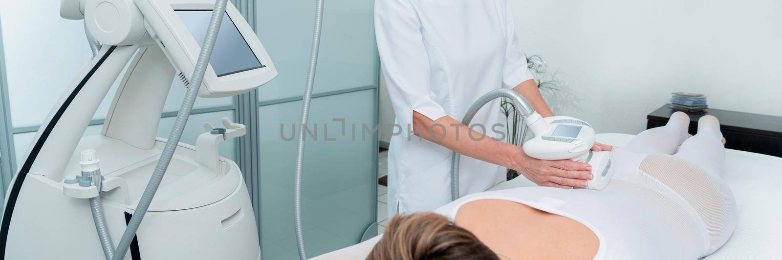 Woman in special white suit getting anti cellulite massage in a spa salon. LPG, and body contouring treatment in clinic. by Mariakray