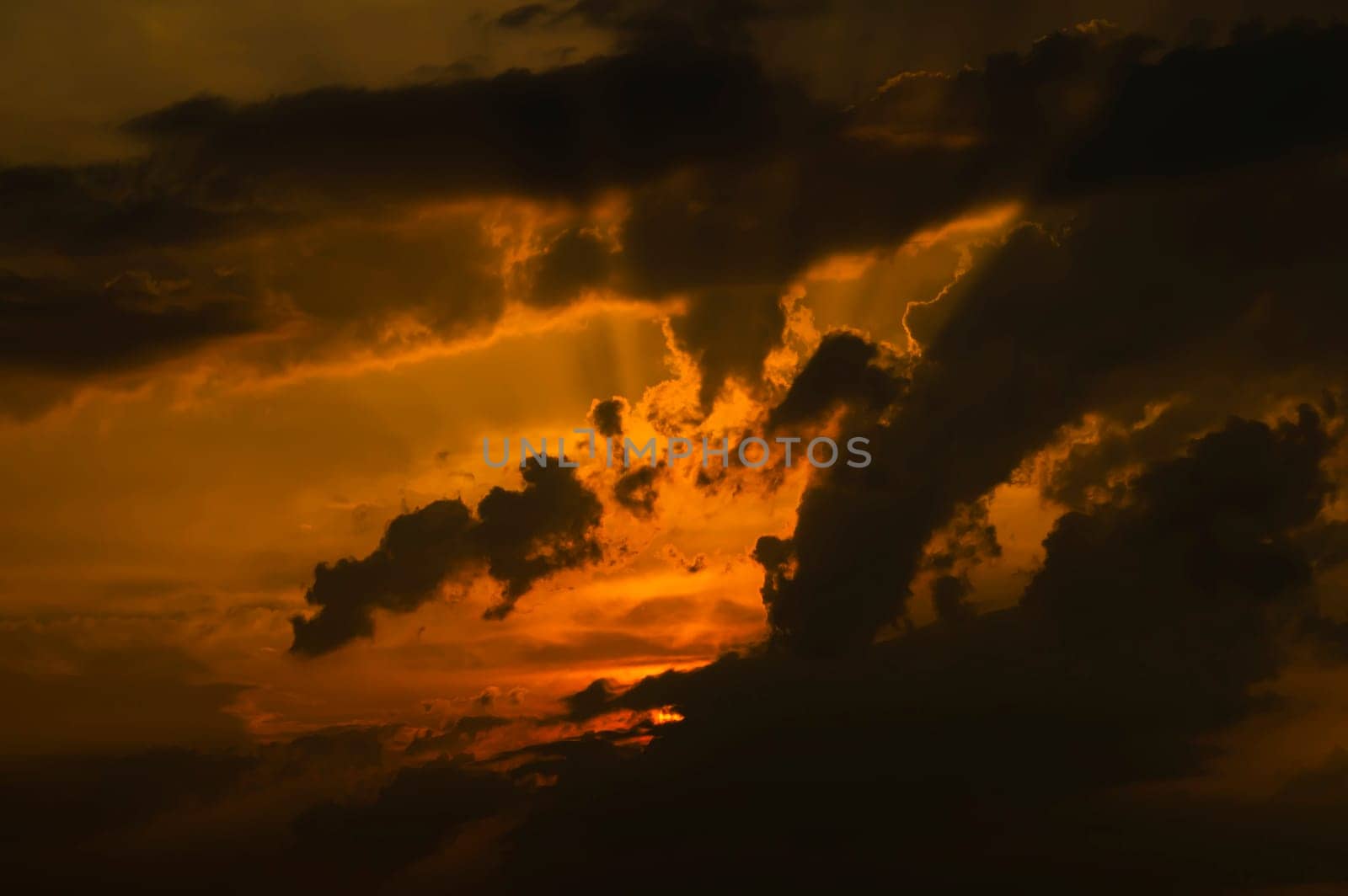 Evening sunrise in the storm clouds of a dramatic sky. The sun behind a dark cloud. Evening sky. Climatic conditions. Weather forecast. Background image.