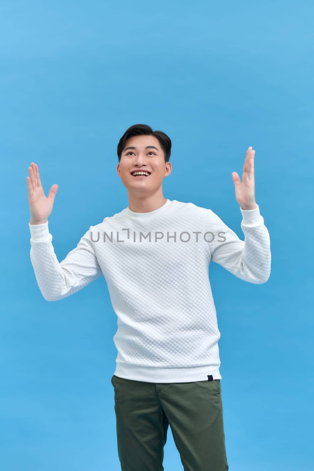 Happy guy rejoicing and clenching fists like winner or lucky person, isolated over blue background by makidotvn