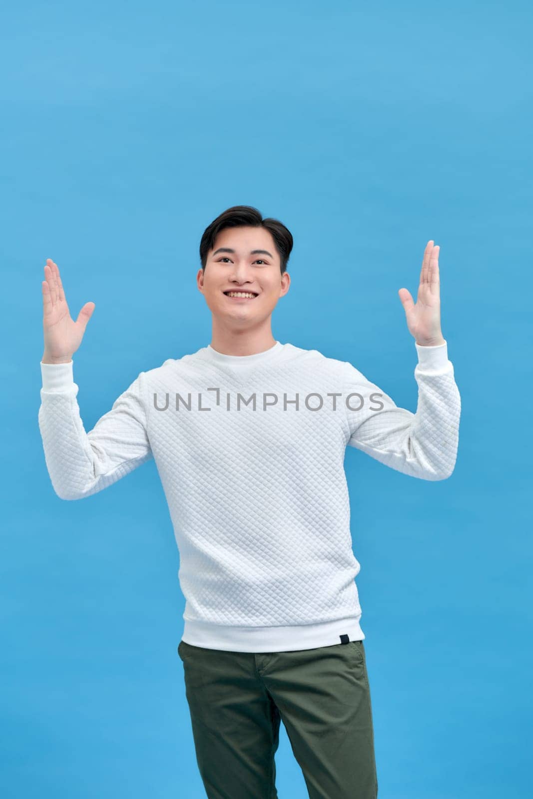 Happy excited young man celebrating his success over blue background by makidotvn