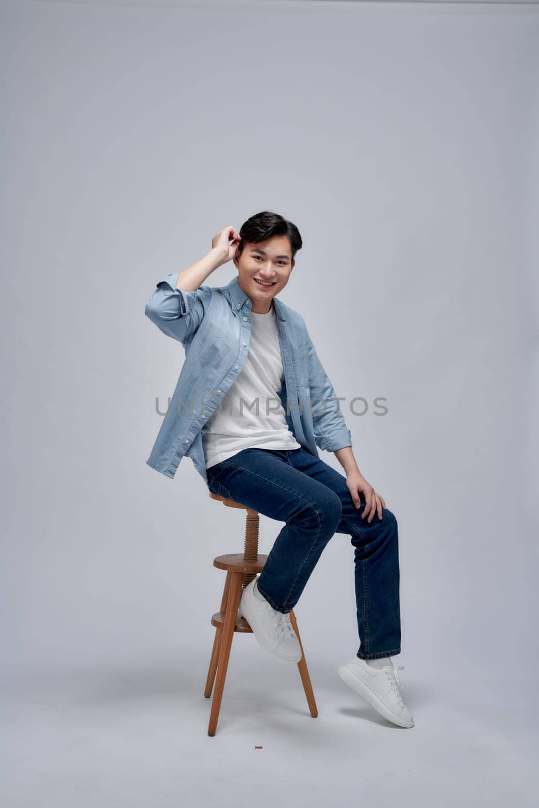 Handsome man sitting on stool against white background by makidotvn