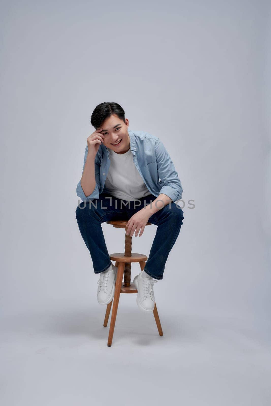 Happy and confident Asian man relaxing while sitting on the chair on white background