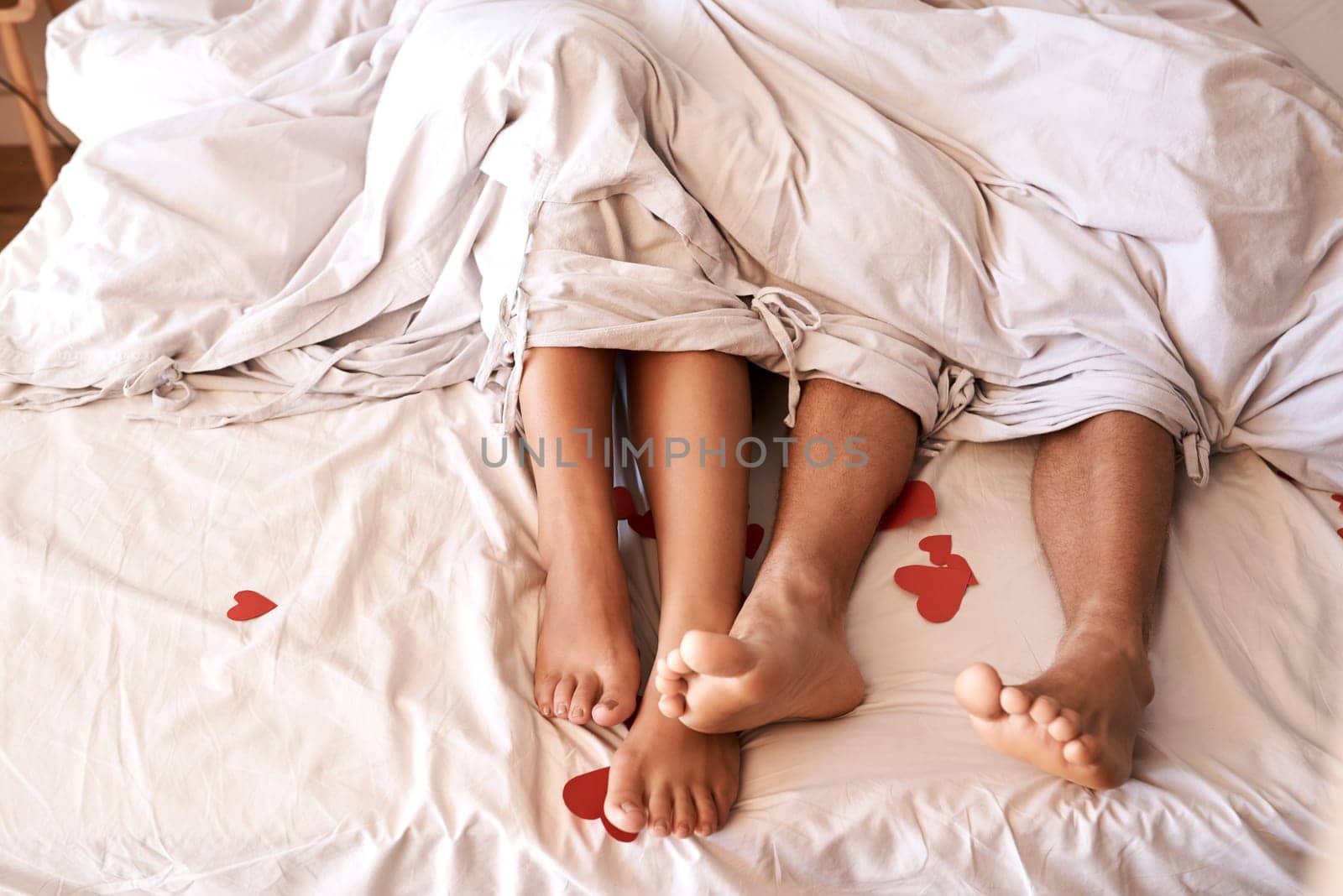 Bed, legs and couple with Valentines Day heart, romance or emoji icon for home love, intimacy and honeymoon affection. Marriage bond, relax sleep and top view feet of people sleeping in hotel bedroom.