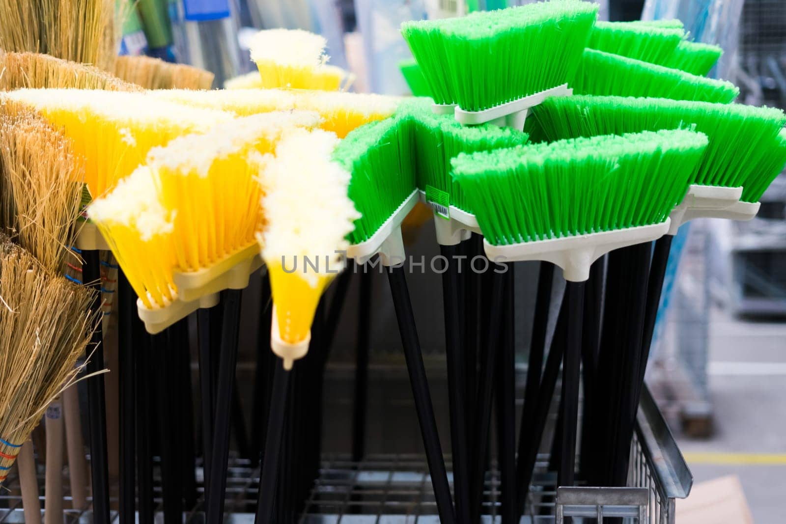 Plastic brushes for cleaning premises. Assortment of multi-colored brooms in store. Close-up