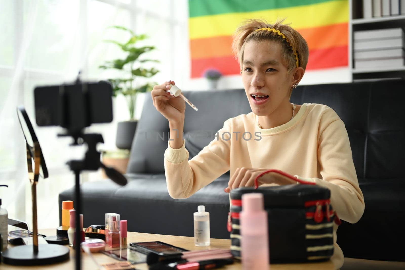 Young queer man beauty make up artist or vlogger recording makeup tutorial in home studio. LGBTQ lifestyle, influencer, blogger.