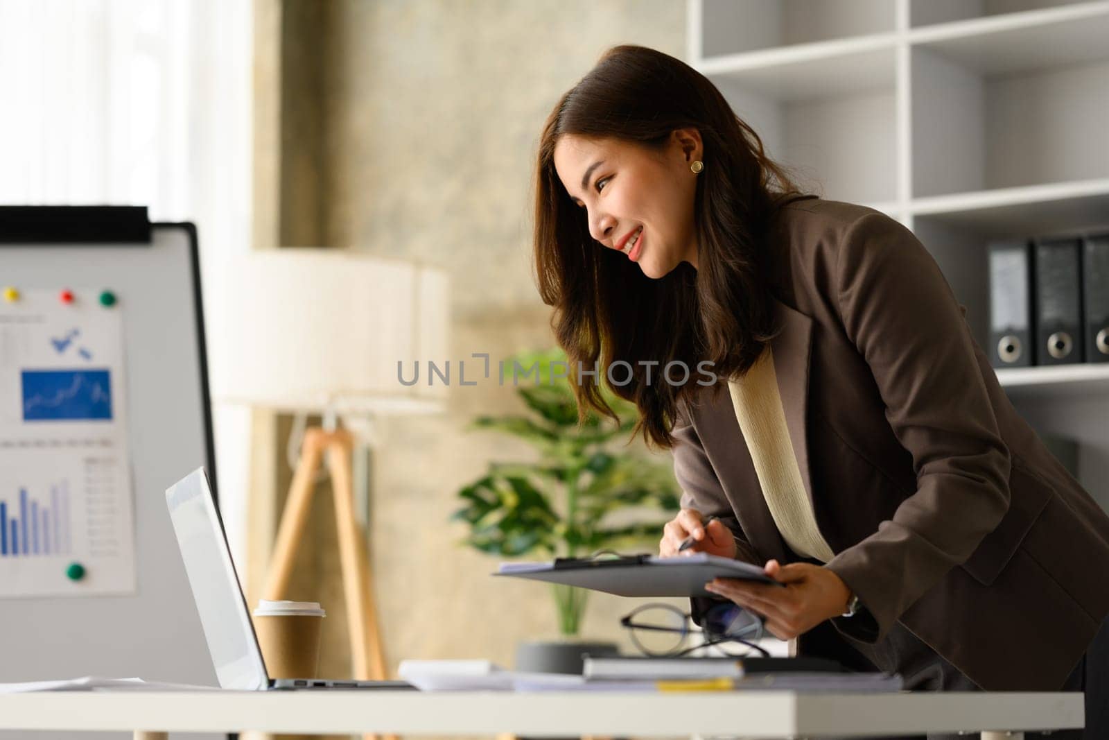 Professional businesswoman analyzing financial data on laptop, stock market information at her workplace.