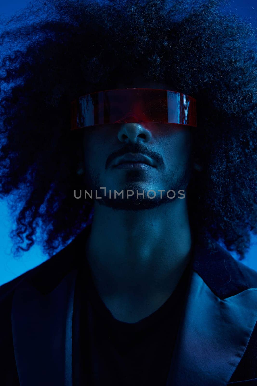Fashion portrait of a man with curly hair on a blue background wearing red sunglasses, multinational, colored light, trendy, modern concept. by SHOTPRIME