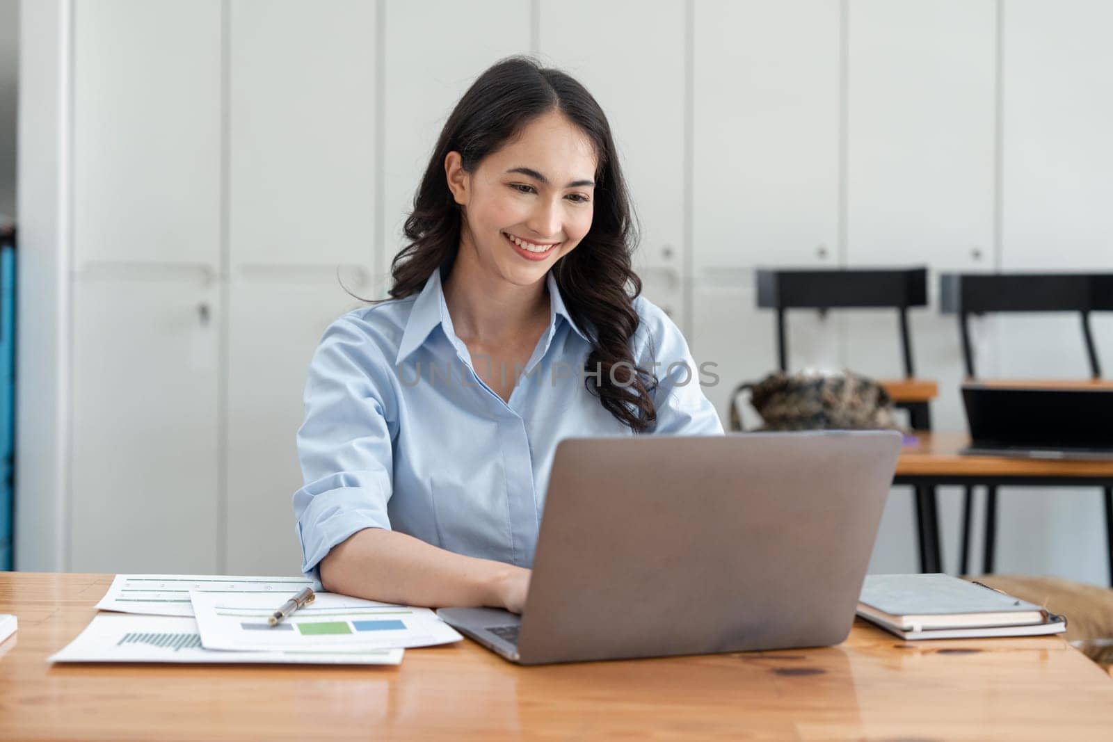 Asian businesswoman working for financial graphs showing results about their investments, planning successful business growth process by laptop computer.